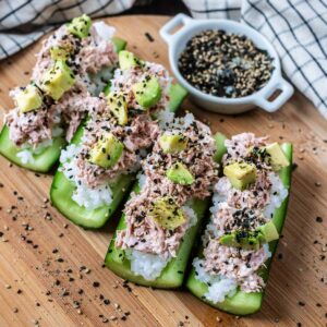 Cucumber sushi boats on a wooden serving board.