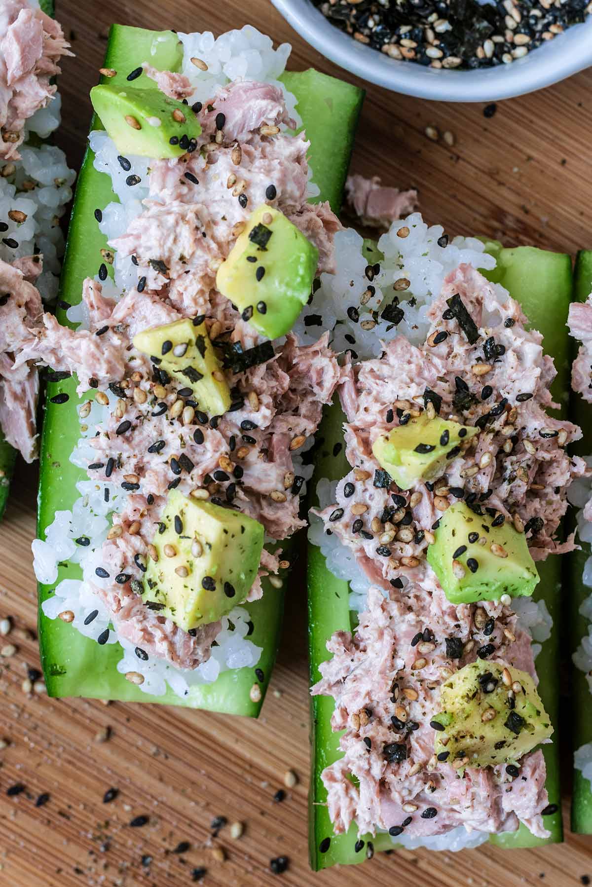 Two cucumber quarters topped with rice, tuna, avocado and sesame seeds.