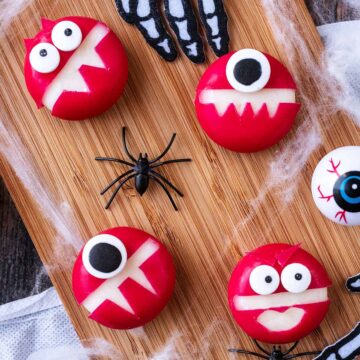 Four Babybel Cheese Monsters on a wooden board.