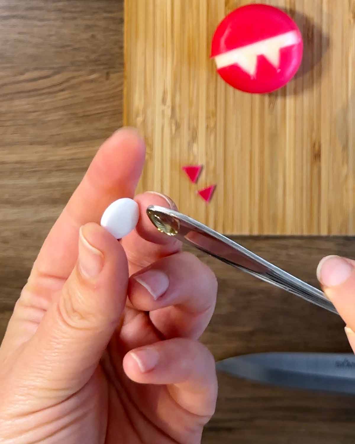 Someone using a teaspoon handle to apply honey to an edible eye.