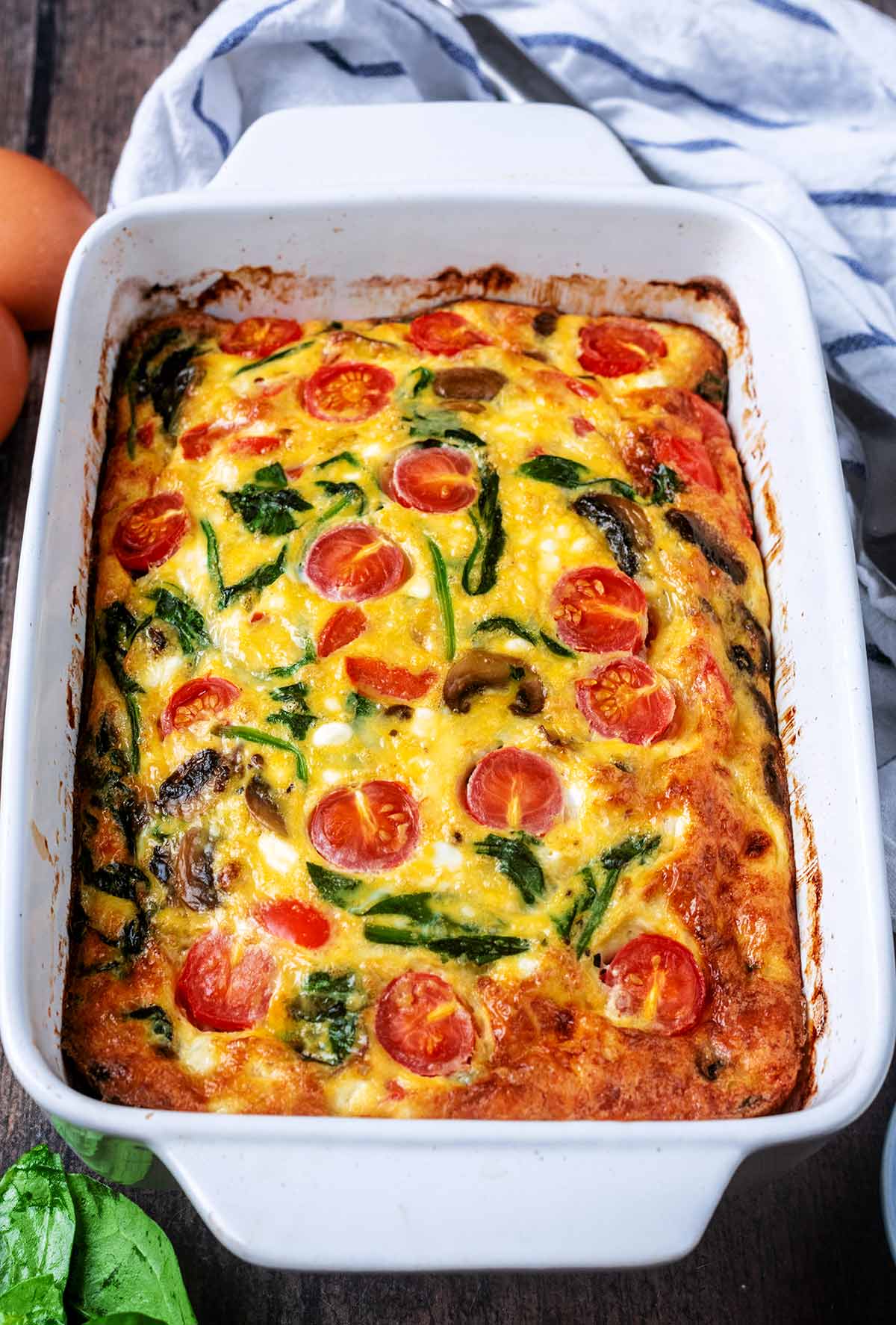 A baking dish full of frittata in front of a striped towel.