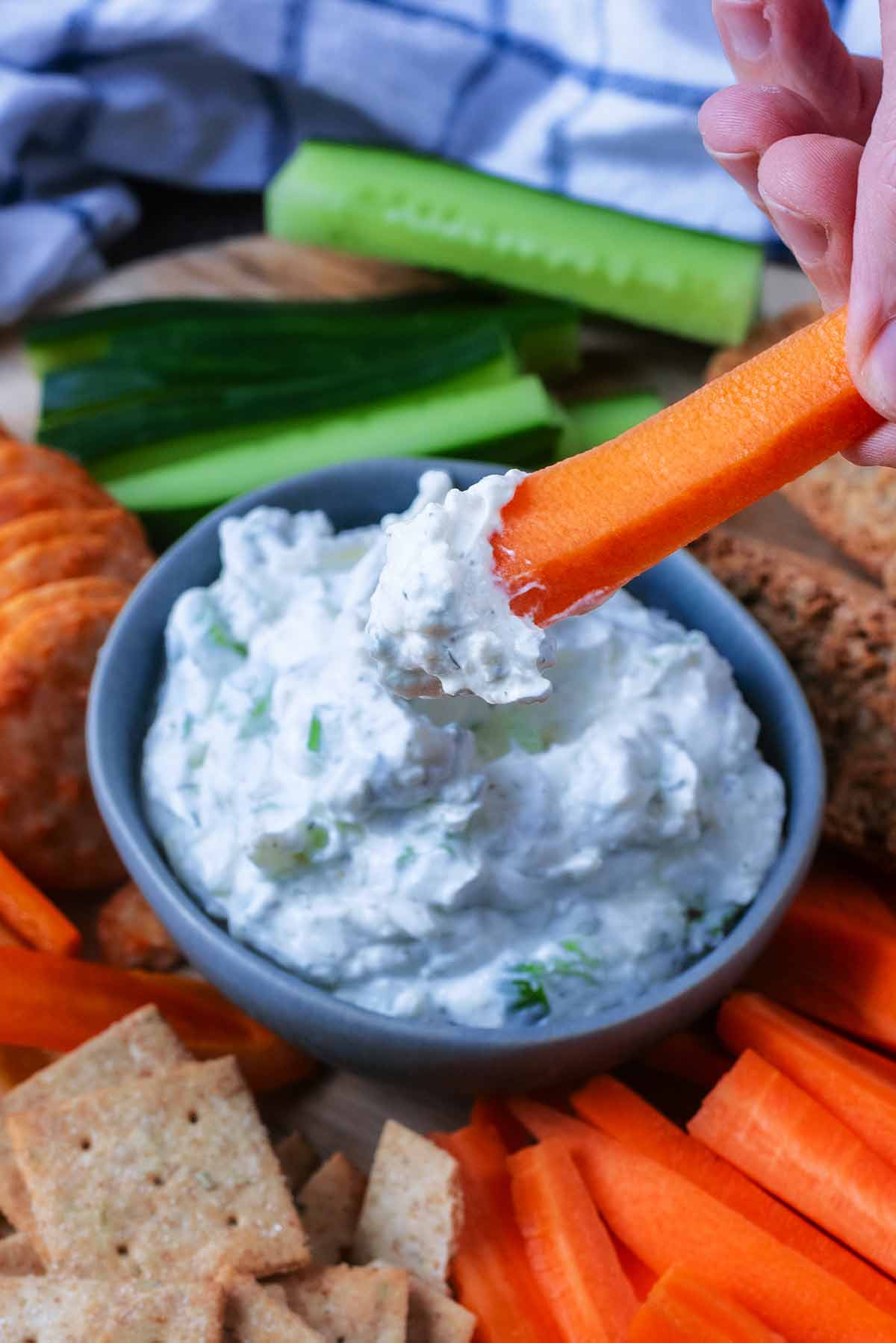 A carrot batten being dipped into a small bowl of creamy dip.