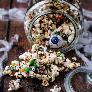 A jar of Halloween popcorn that has fallen over and popcorn has spilled out.