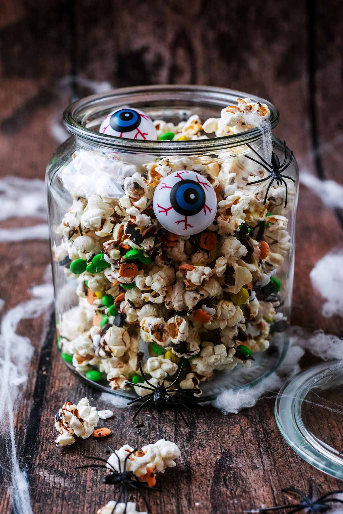 A jar of Halloween themed popcorn with. false eyes in it.