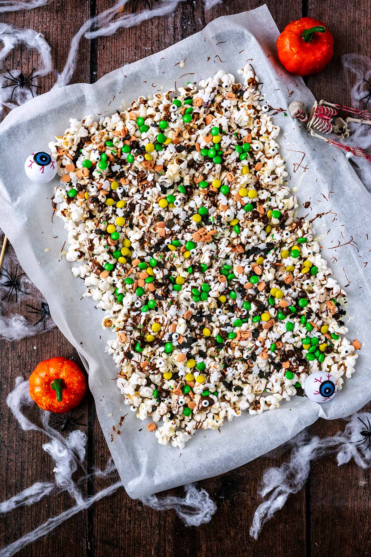 Popcorn spread on a baking sheet next to Halloween decorations.