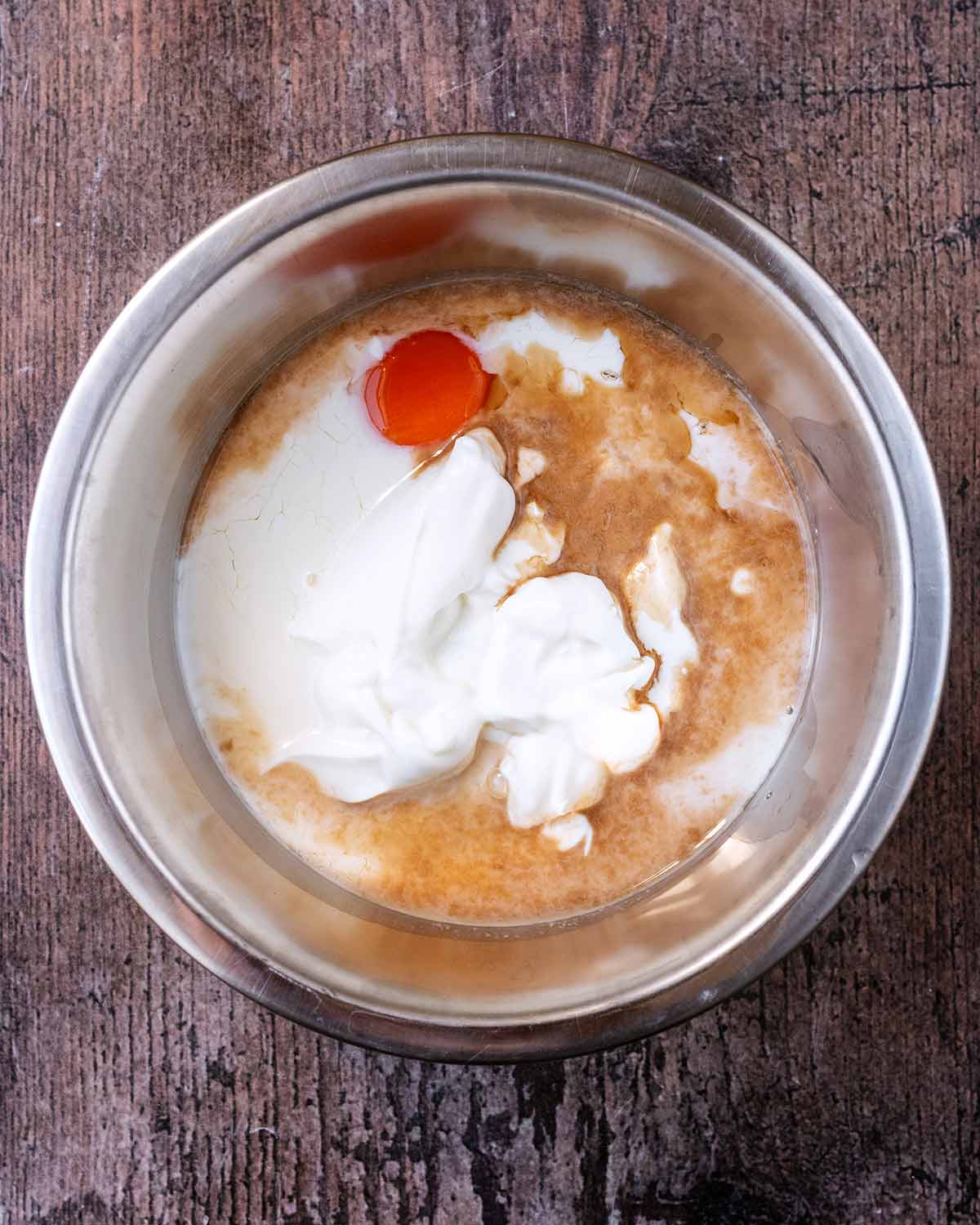 A mixing bowl with milk, egg, yogurt and vanilla in it.