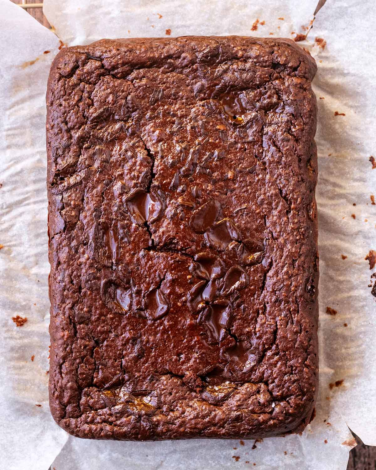 A slab of cooked brownie on a sheet of parchment paper.