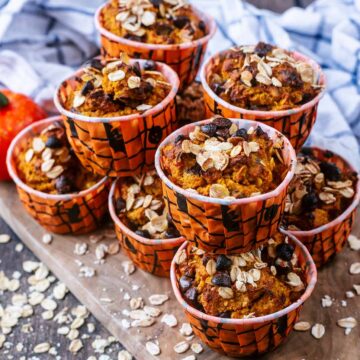 A pile of healthy pumpkin oat muffins on a wooden board.