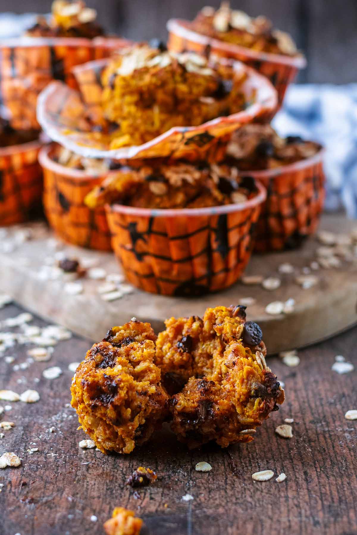 A pumpkin muffin, broken in half, with more muffins in the background.