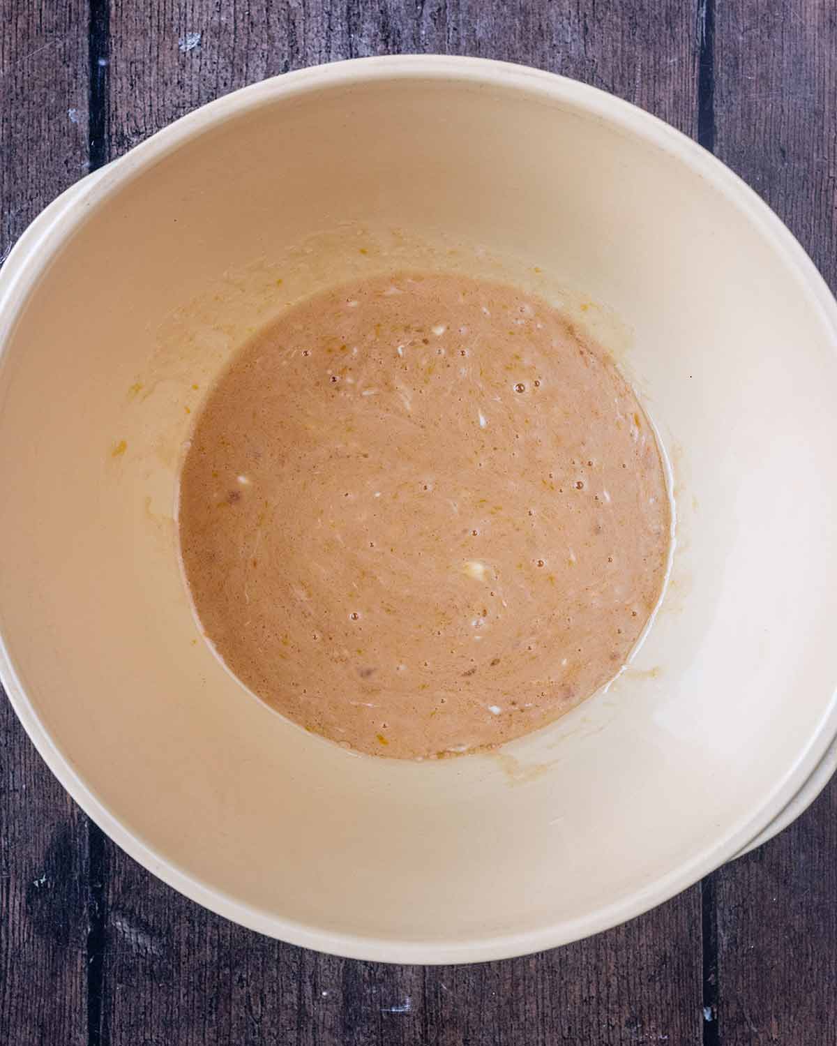 A mixing bowl with egg, oil, maple syrup vanilla and yogurt mixed together.