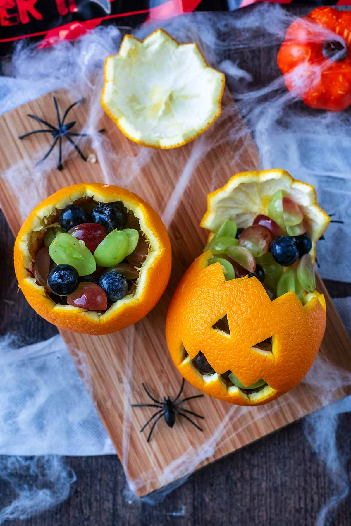 Two oranges, flesh removed and filled with berries.