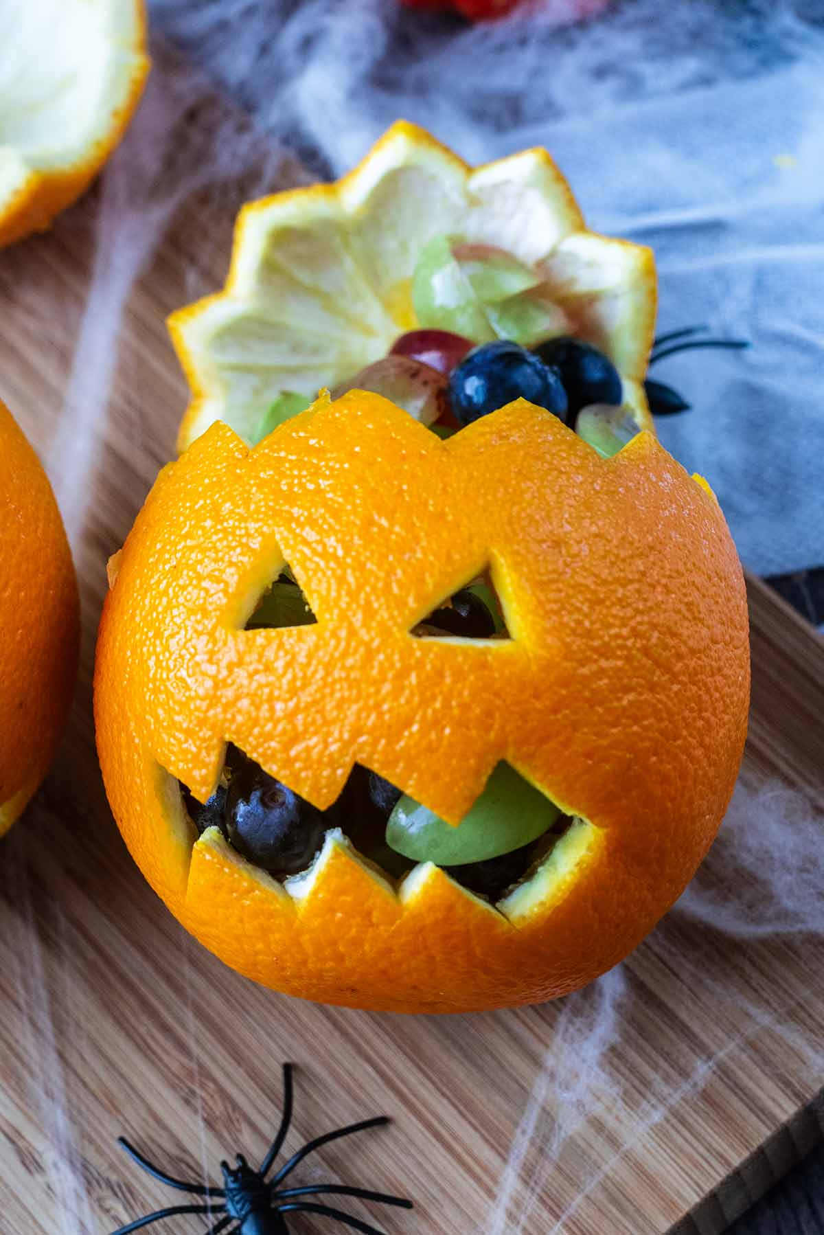 An orange that has been scooped out and filled with berries.