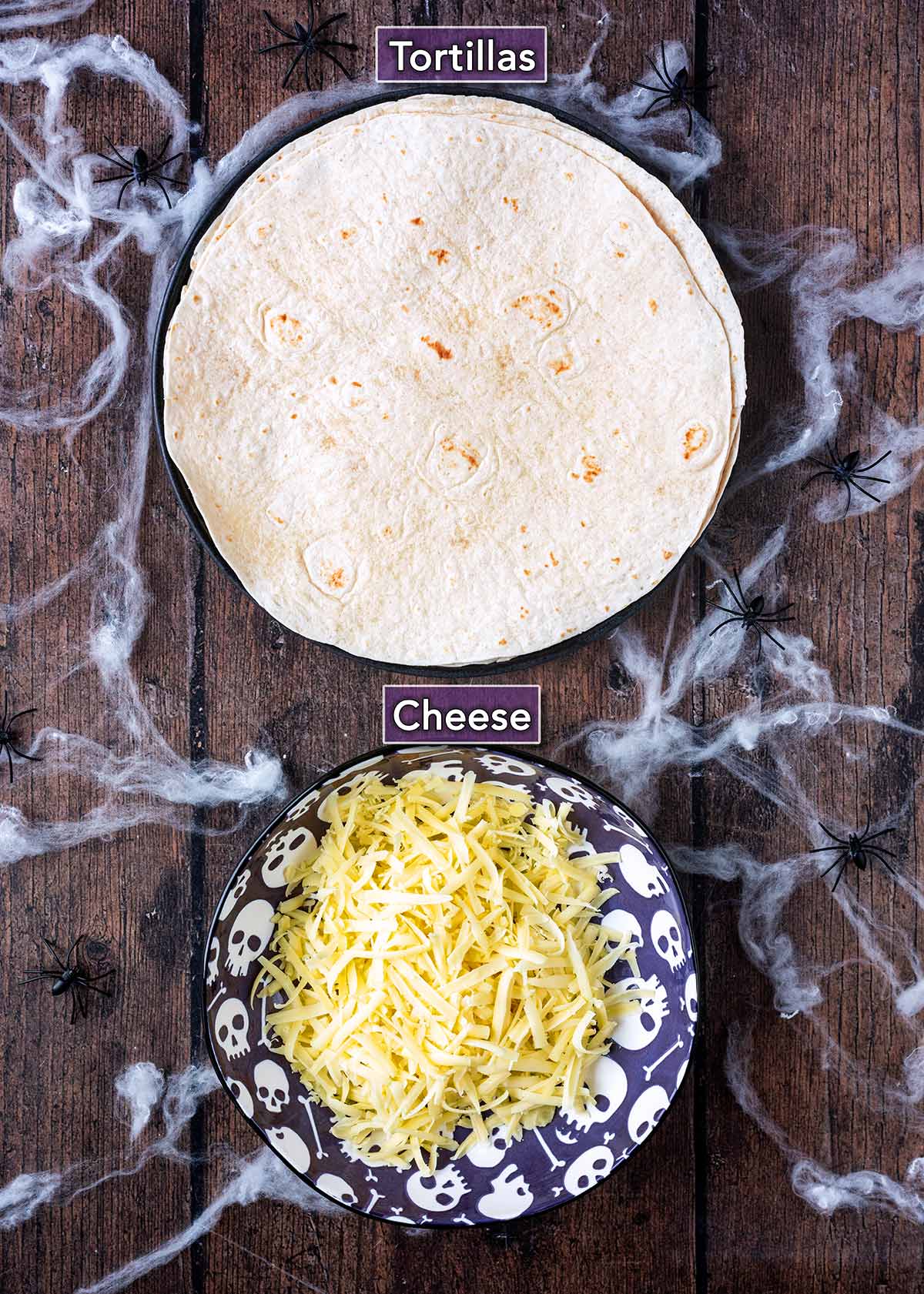 Flour tortillas and a bowl of grated cheese surrounded by fake cobwebs.