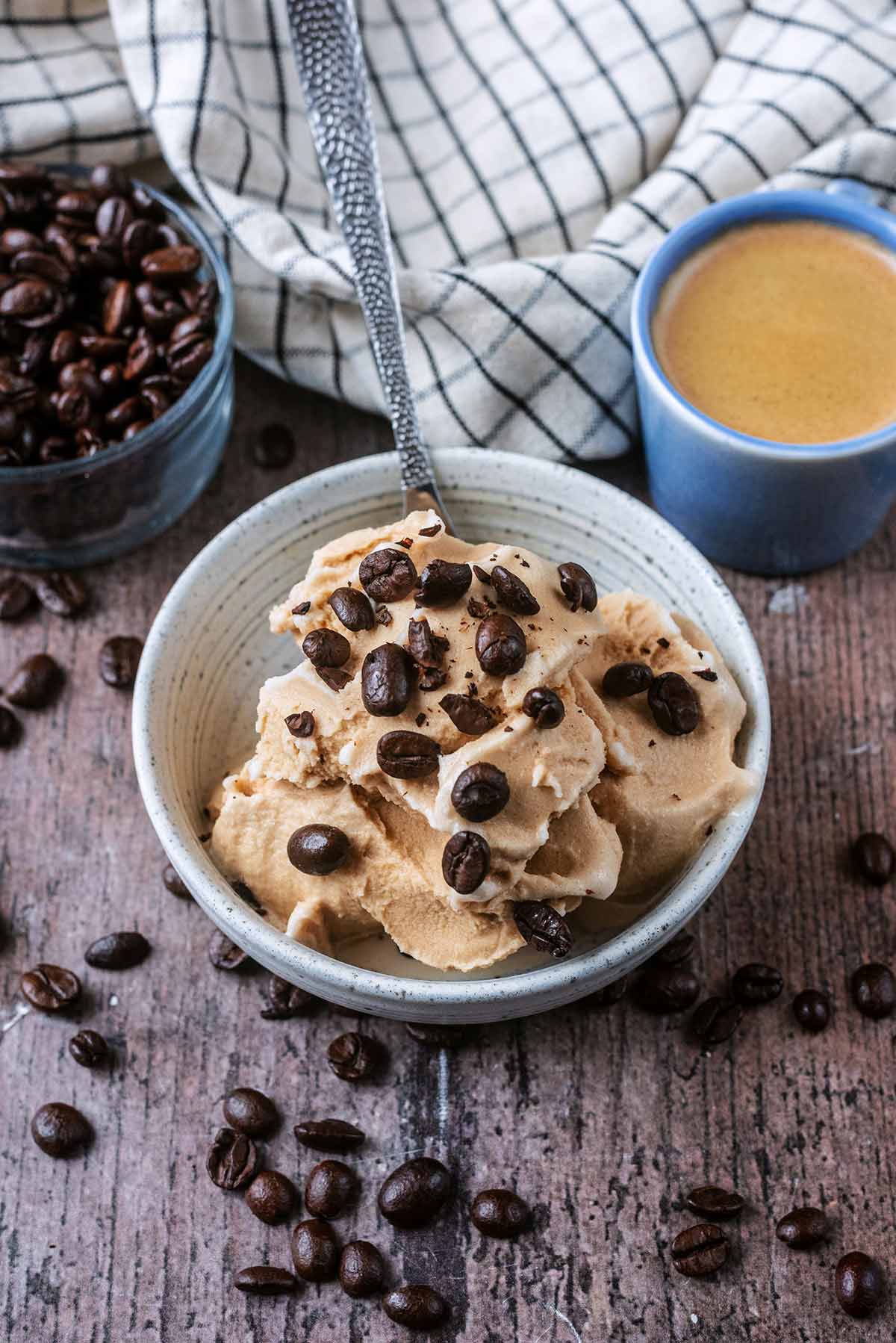 Coffee ice cream in a bowl with a spoon and a small cup of espresso next to it.