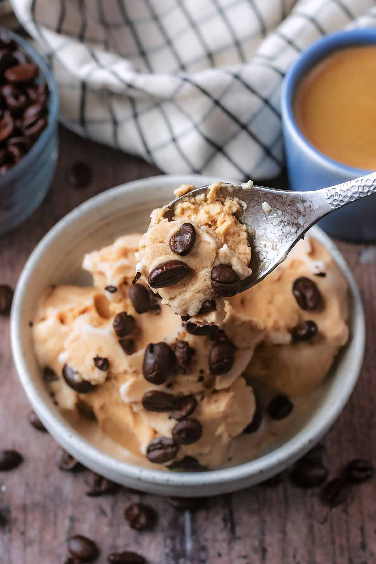 A spoon lifting some coffee ice cream from a bowl.