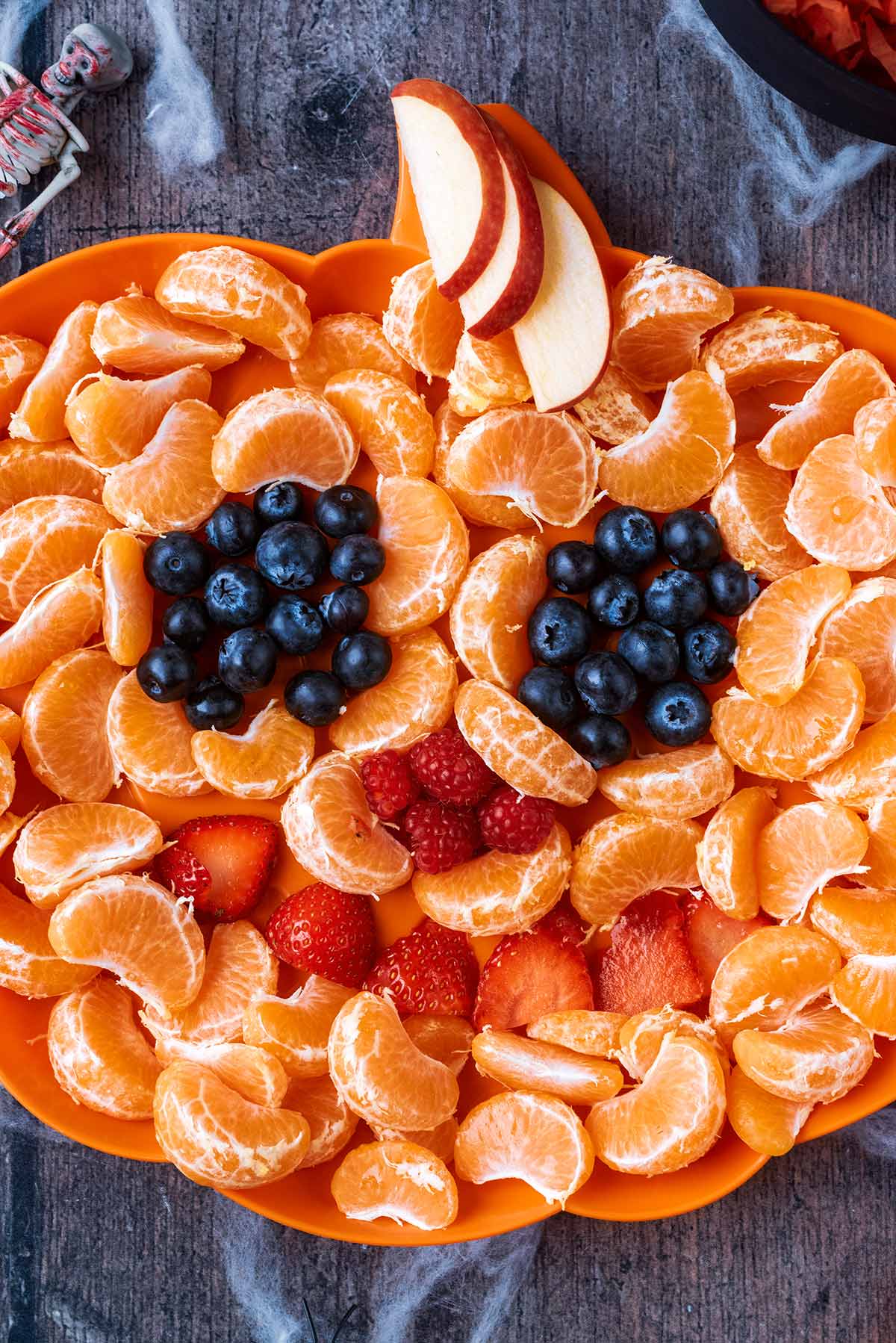 Oranges and berries in a Jack-O'-Lantern design.