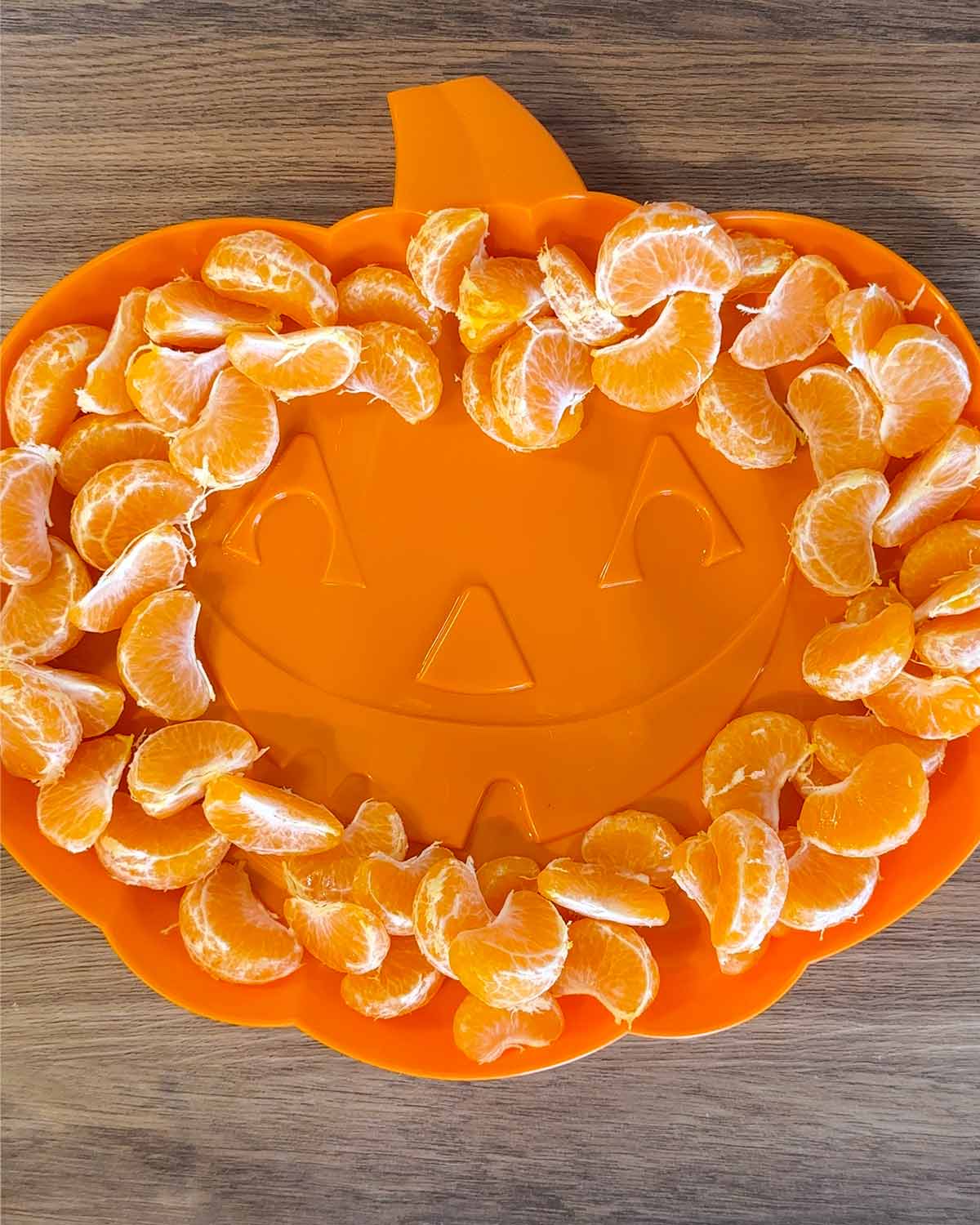 A pumpkin shaped platter with orange segments on it.