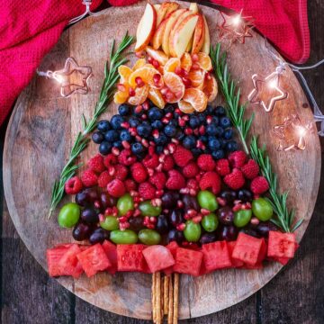 A Christmas Fruit Tray on a wooden surface next to a red towel.