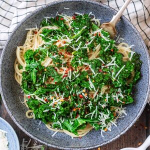 A bowl of Garlic Parmesan Kale Pasta next to a checked towel.