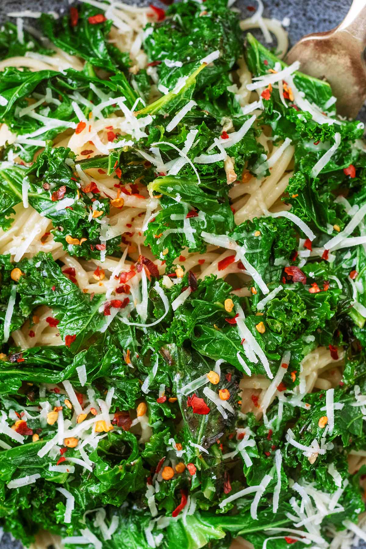 Cooked kale mixed into spaghetti and topped with red chilli flakes.