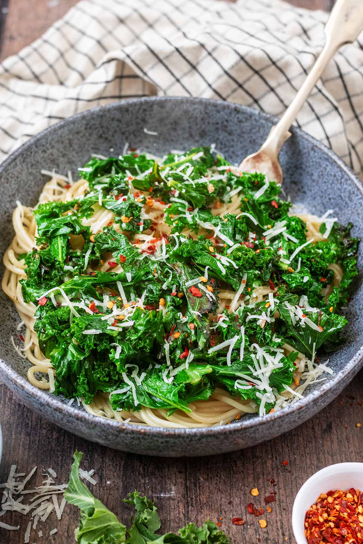 A fork in a large bowl of spaghetti and kale.