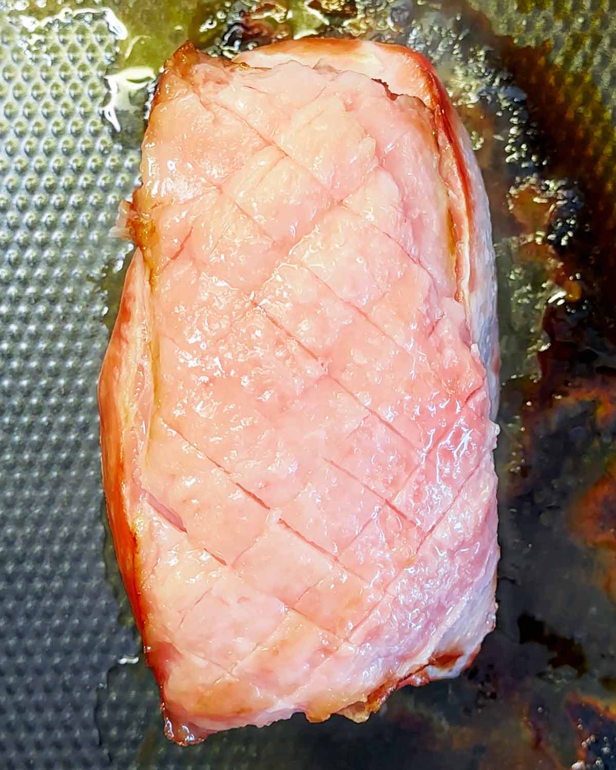 Cooked ham joint with the fat removed and a diamond pattern scored in the top.