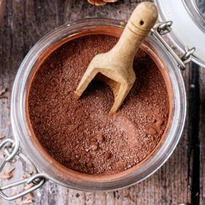 A jar of homemade hot chocolate mix with a small wooden spoon in it.