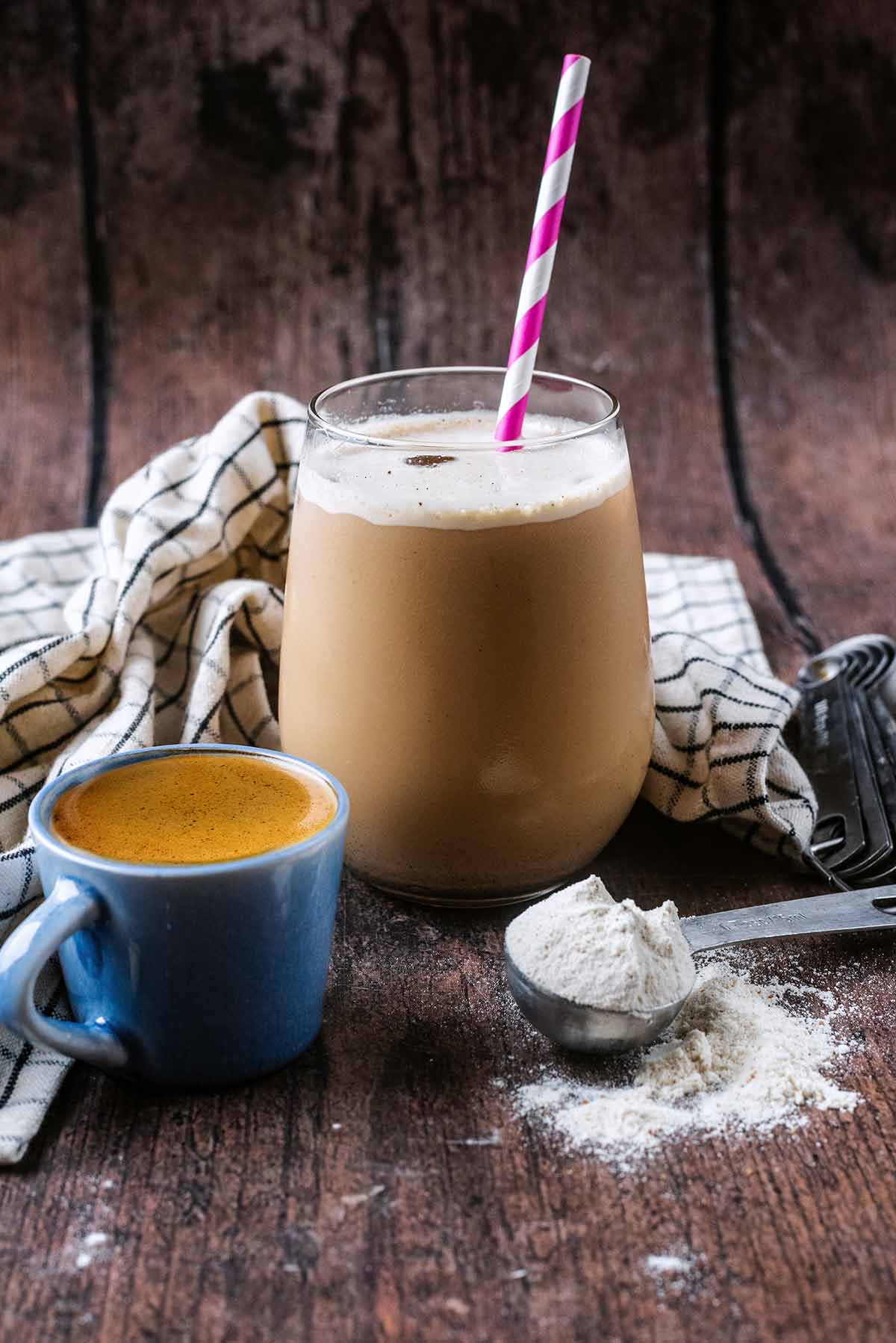 An iced cafe latte in a glass with a small cup of espresso coffee next to it.