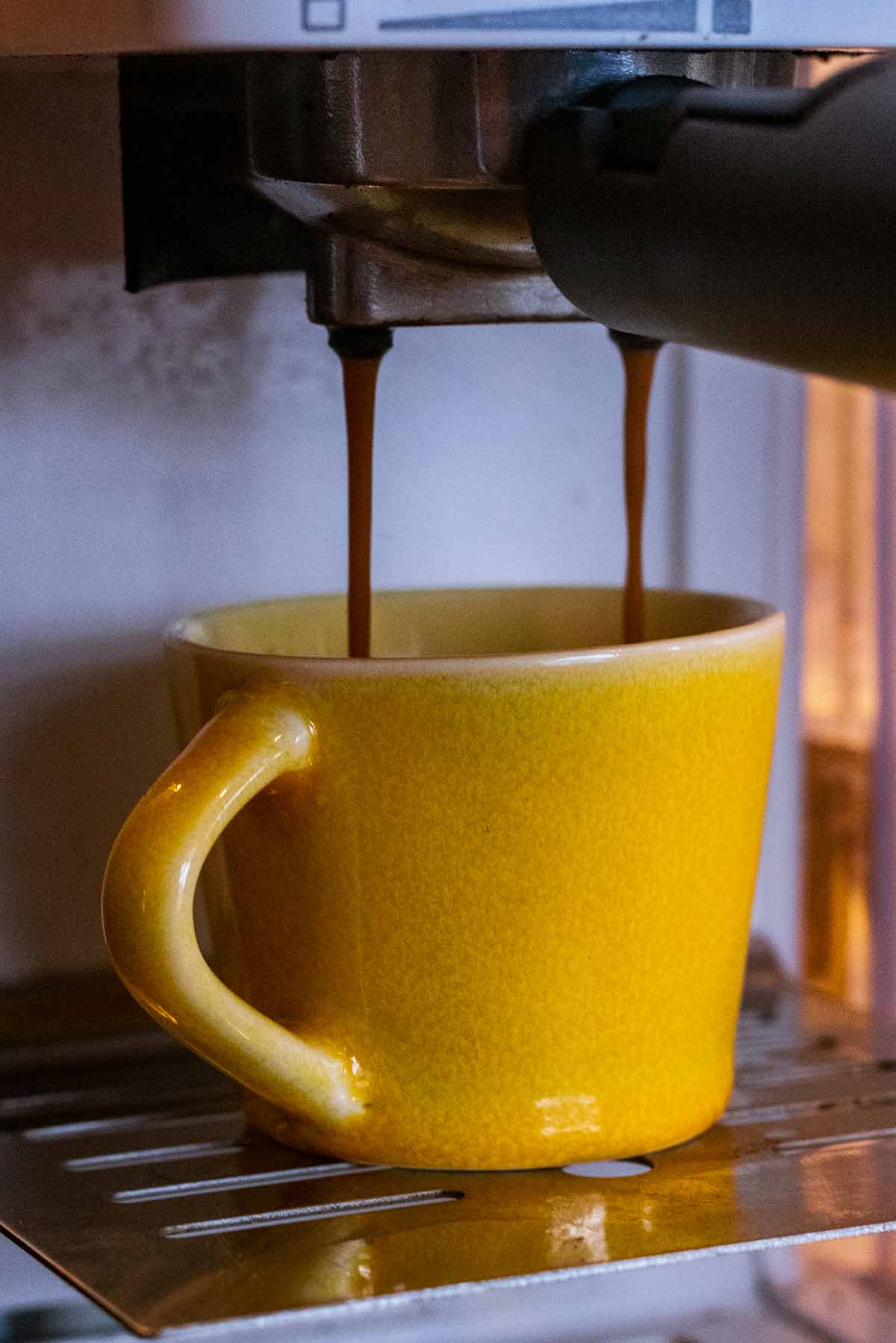 A cup of espresso being brewed in a machine.