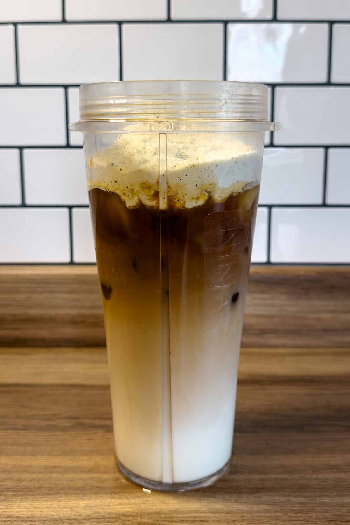 A tall jug with milk, ice, coffee and protein powder in it.