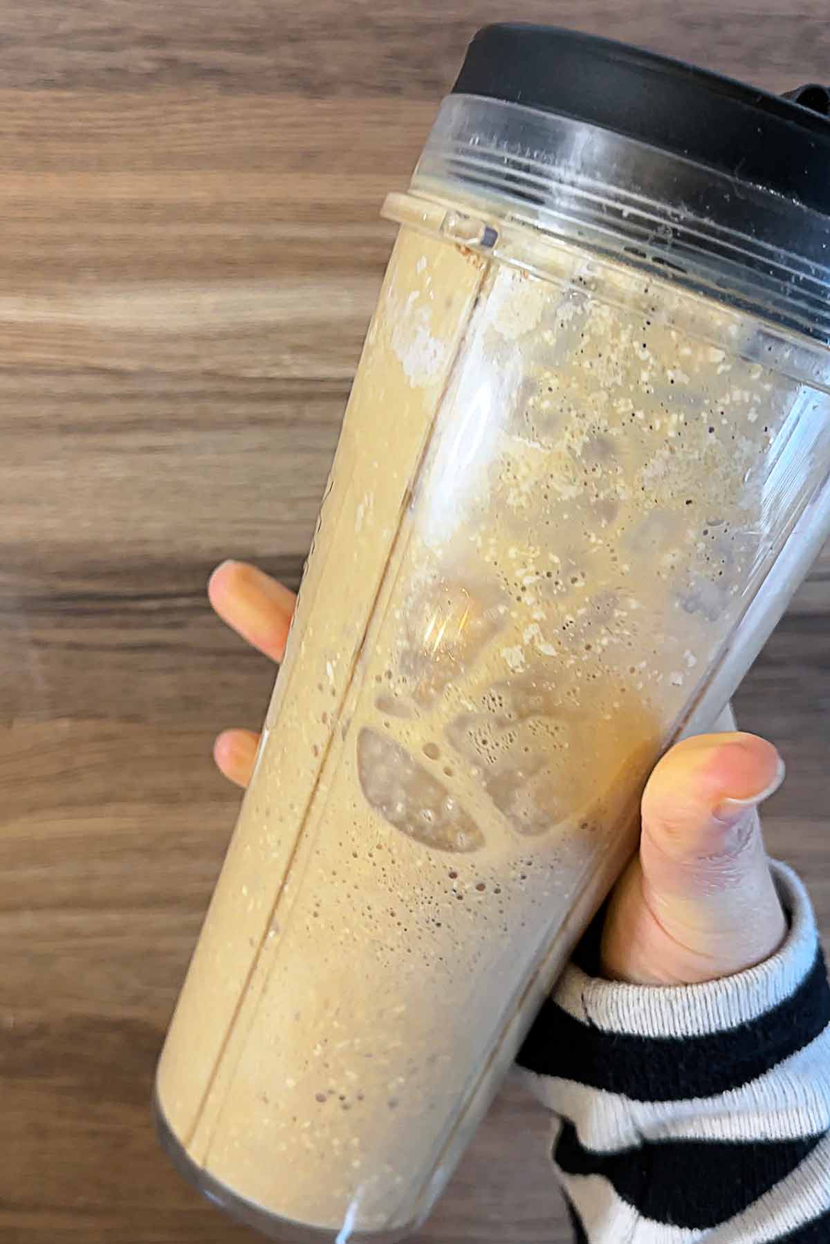 A hand shaking the jug of iced latte.