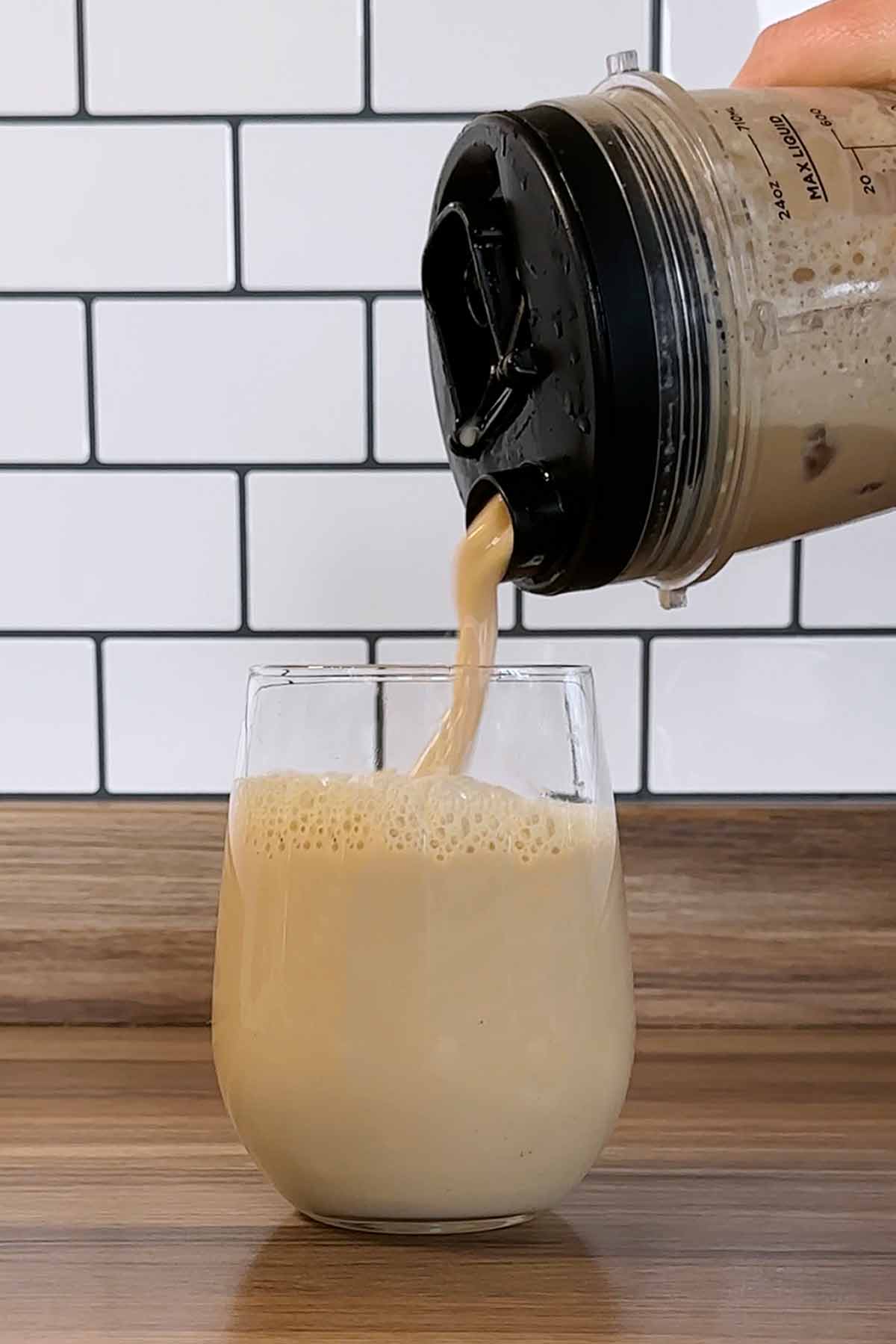 Iced latte being poured into a glass.