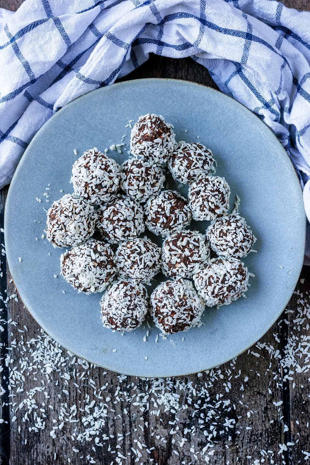 Coconut covered energy balls on a round grey plate.