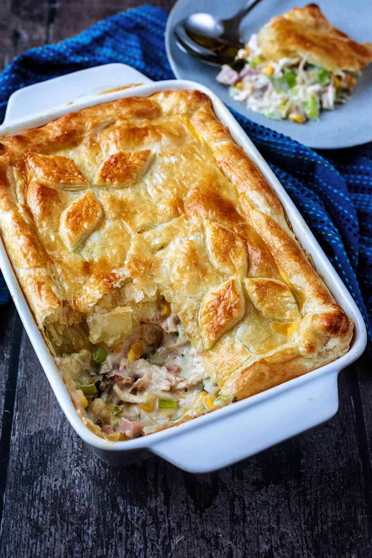 Ham and chicken pie in front of a portion of more pie in the background.