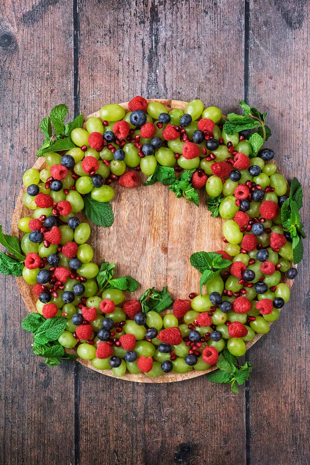 Berries arranged on a round wooden board to look like a Christmas wreath.