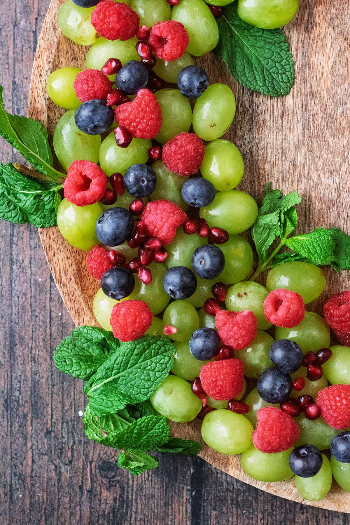 Grapes, raspberries, blueberries and mint leaves arranged like a wreath.