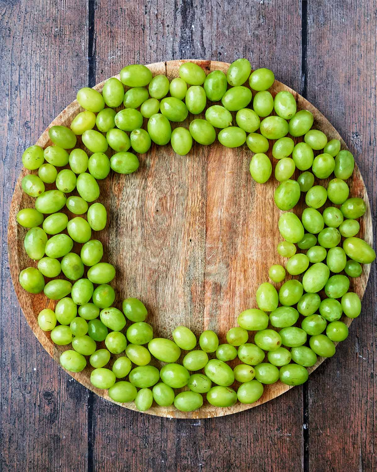 Green grapes arranged into a large ring on a circular serving board.