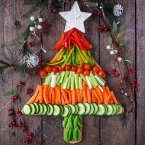 A Christmas Veggie Tray on a wooden surface surrounded by Christmas decorations.