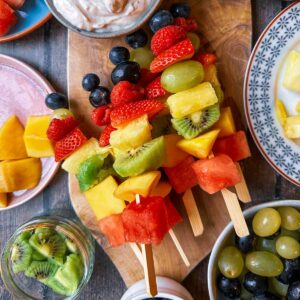 Fruit kebabs on a wooden serving board.