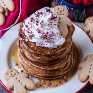 A stack of gingerbread pancakes with cream and a gingerbread person on top.