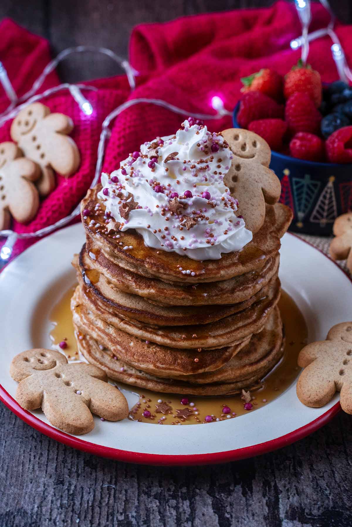 A stack of pancakes in front of a red towel and some Christmas decorations.