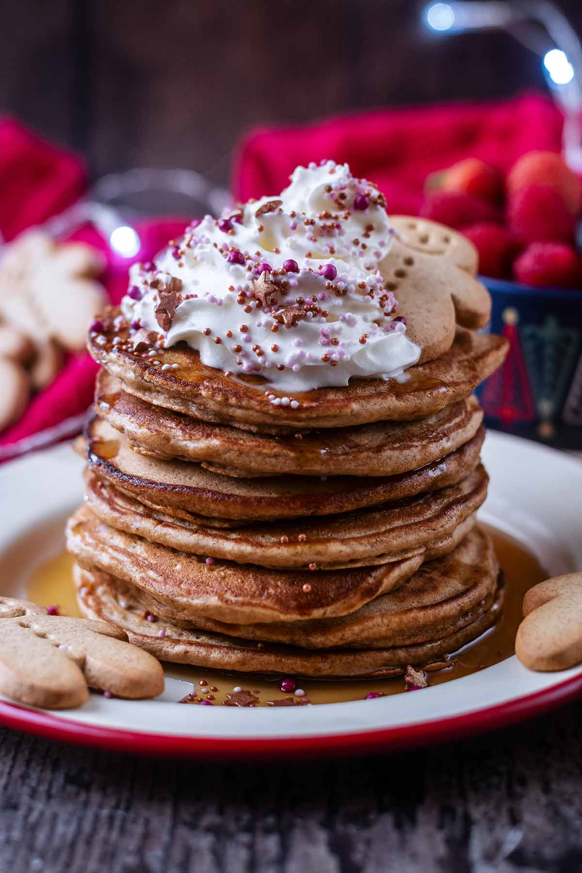 A stack of pancakes with maple syrup dripping down the sides. Whipped cream is on the top.