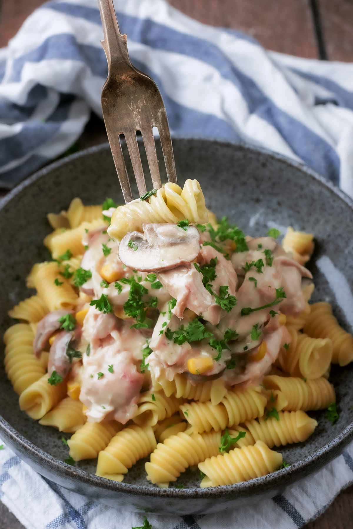 A fork lifting some turkey fricassee from a bowl.