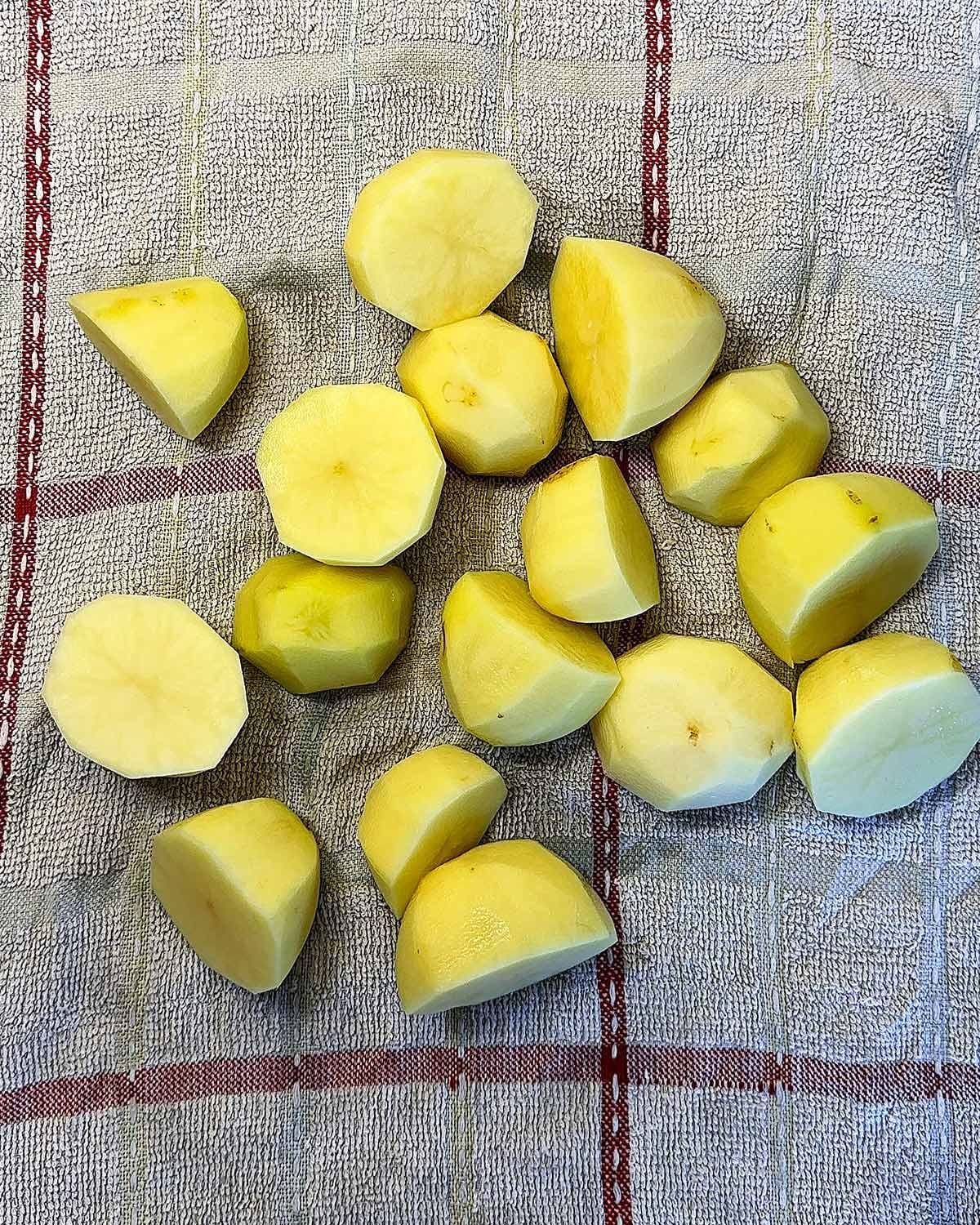 Uncooked, peeled potatoes on a towel.