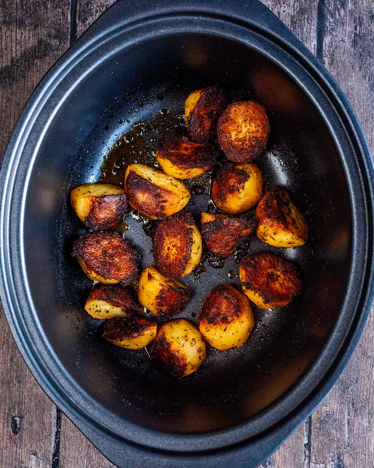 Cooked roast potatoes in a slow cooker bowl.