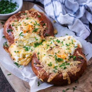 Two air fryer breakfast bagels on a piece of parchment paper.