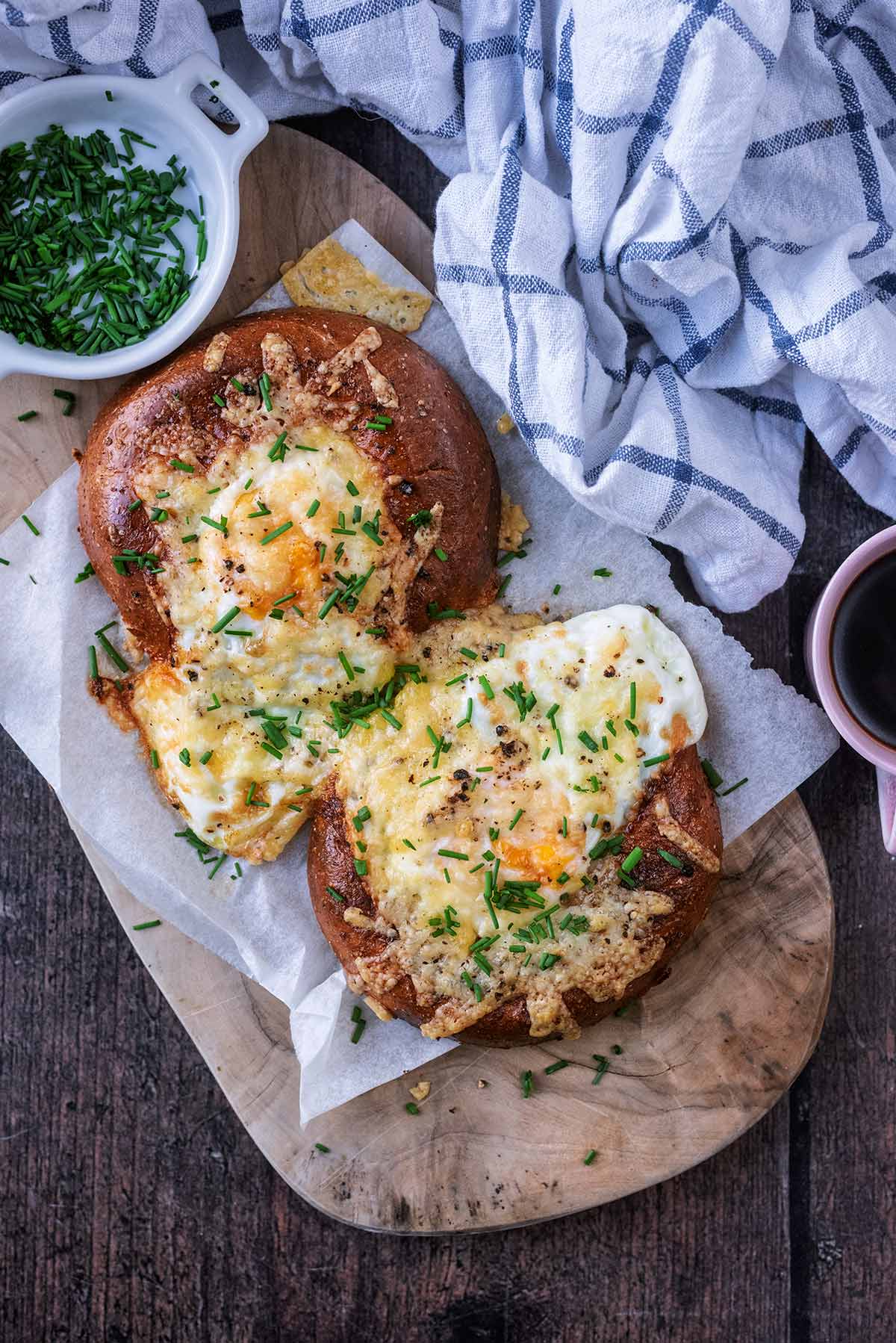 Cooked eggs in bagel halves topped with melted cheese and chopped chives.