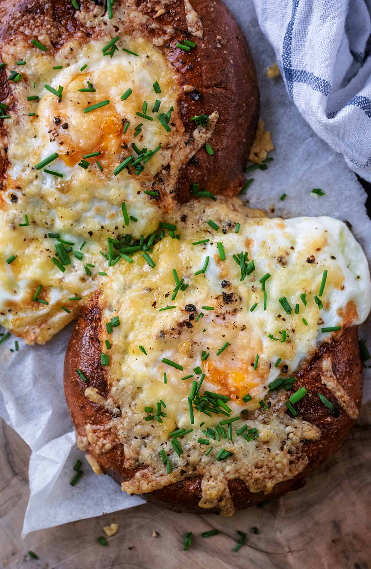 Melted cheese and chopped chives on top of a cooked egg in a bagel.