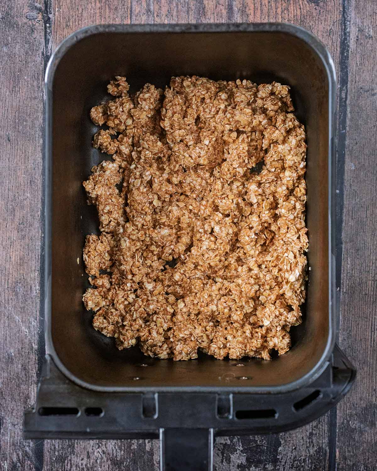 Uncooked granola in an air fryer basket.