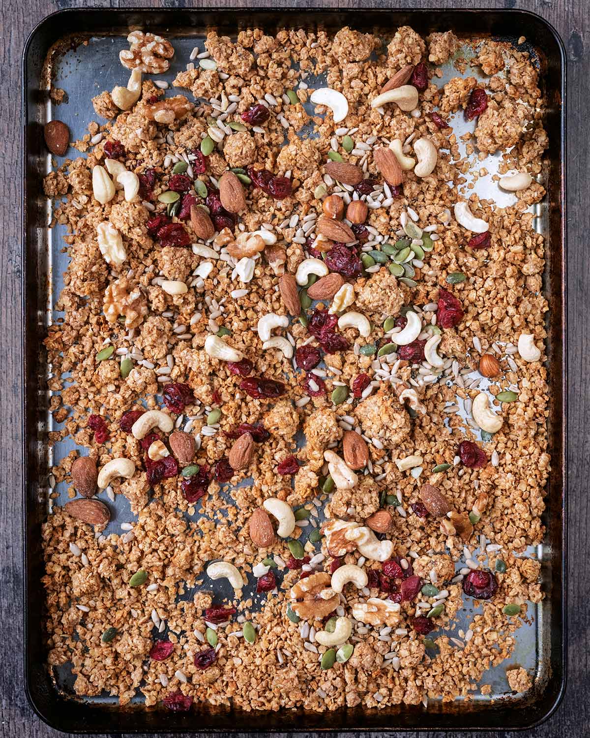 A tray of granola with nuts, seeds and dried fruit added.